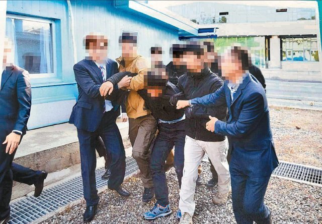 2019년 11월 7일 탈북 어민 중 한 명이 판문점에서 북송을 거부하며 몸부림치자 정부 관계자들이 팔을 붙잡아 제압하고 있다. 통일부 제공