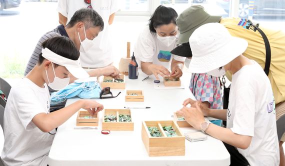 지난 6일 리얼스 프로그램의 하나로 진행된 '바다유리 액자 만들기' 행사에 고객들이 참여해 즐거운 시간을 보내고 있다. 롯데백화점 제공