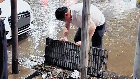 지난 8일 서울 남부에 시간당 100mm ‘물폭탄’이 쏟아진 가운데 서울 강남역 인근에서 한 남성이 맨손으로 막힌 배수로를 뚫고 있다. 사진 온라인 커뮤니티