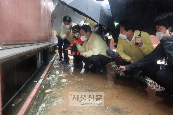 민방위복 입고 지하 살피는 尹  - 윤석열 대통령이 9일 간밤의 폭우로 발달장애인 일가족이 숨진 서울 관악구 신림동의 다세대주택을 찾아 쪼그려 앉은 채 반지하 창문으로 안을 살펴보고 있다. 윤 대통령은 이날 처음으로 민방위복을 입었다.박지환 기자