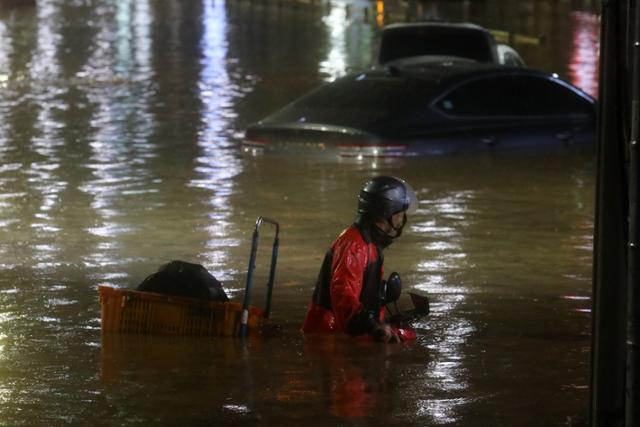 서울과 경기남부 등 수도권에 폭우가 내린 8일 서울 강남구 일대 도로가 침수돼 오토바이를 탄 것으로 보이는 운전자가 어렵게 이동하고 있다. 뉴시스