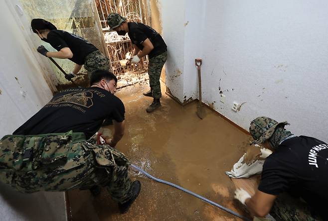 육군 특전사 1공수여단 장병들이 폭우로 산사태가 발생하며 토사가 유입되고 침수 등의 피해를 입은 서울의 한 가정에서 토사 제거 및 가구 등 물품을 옮기는 대민 지원을 하고 있다. [연합]