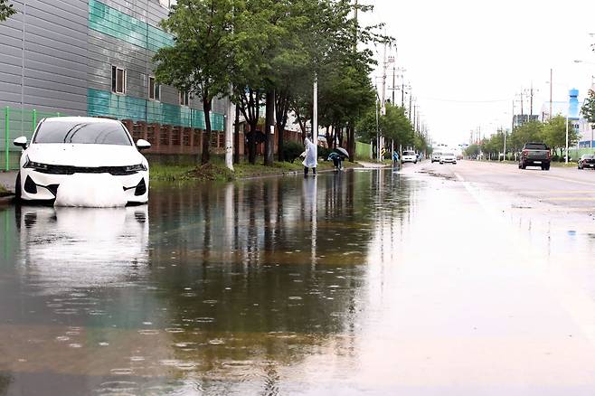 폭우 특보가 내려진 11일 오후 전북 군산시 오식도동의 한 도로에서 군산시 공무원들이 배수 작업을 하고 있다. 사진은 기사 내용과 관련 없음. [연합]
