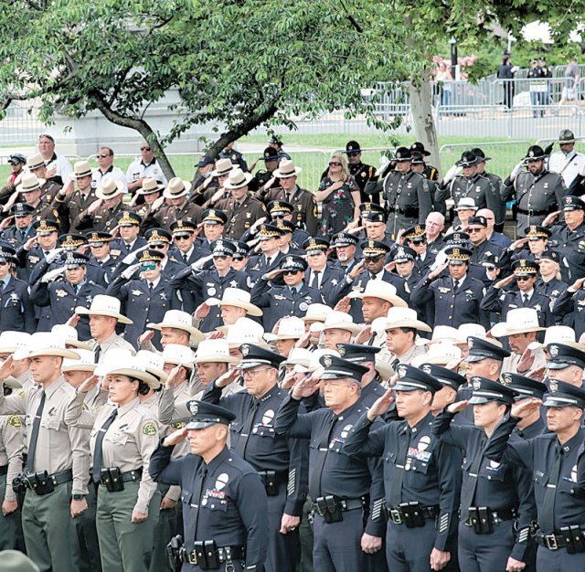 올해 5월 15일 미국 워싱턴에서 열린 ‘국가평화경찰추모식’에서 경찰관들이 유가족들에게 경례를 하고 있다.