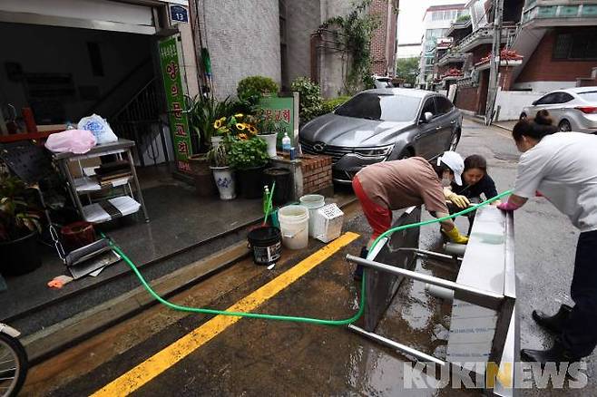 13일 오후 관악구 신사로 10길 양의문교회 입구에서 이 교회 신도들이 지하 교회에서 꺼낸 집기들을 물에 씻고 있다.