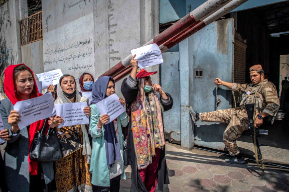 - 아프가니스탄 여성들이 19일(현지시간) 카불의 옛 여성부 청사 앞에서 탈레반 대원이 지켜보는 가운데 여성 권리 증진을 요구하는 시위를 벌이고 있다.AFP 연합뉴스