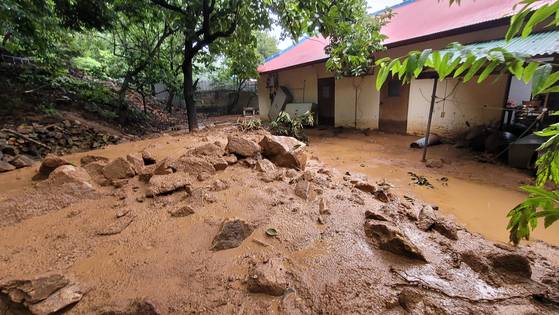 충남 청양군에 집중호우가 내린 14일 새벽 장평면 화산리 한 주택 뒷마당에 인근 야산에서 쏟아져 내려온 토사가 쌓여 있다. 〈사진=연합뉴스〉
