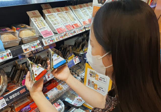 고객이 이마트24 매장에서 더빅삼각김밥을 구입하고 있다