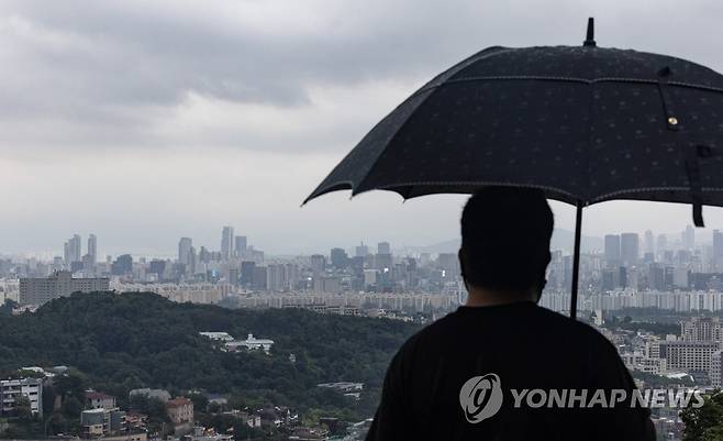 지난 8일 오후 서울 남산 전망대에서 한 시민이 우산을 쓰고 용산과 강남 일대를 보고 있다. [연합뉴스 자료사진. 재판매 및 DB 금지]