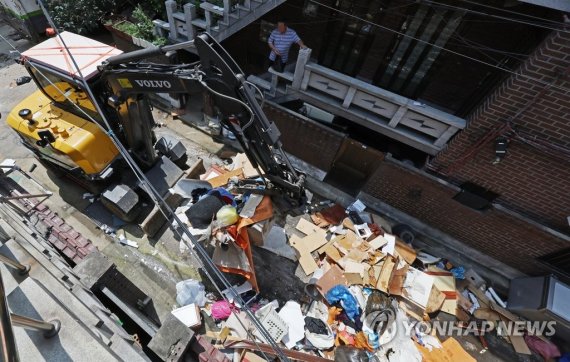 지난 14일 오후 서울 관악구 신사동 일대 수해 피해 현장에서 환경미화원들이 굴삭기를 이용해 복구 작업을 하고 있다. /연합뉴스