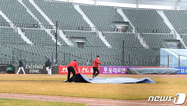 1일 오후 부산 사직야구장에서 열린 2021시즌 첫 연습경기 롯데 자이언츠와 삼성 라이온즈 경기에서 3회초 비로 인해 경기 취소가 결정되자 관계자가 방수포를 덮고 있다. 2021.3.1/뉴스1 ⓒ News1 여주연 기자