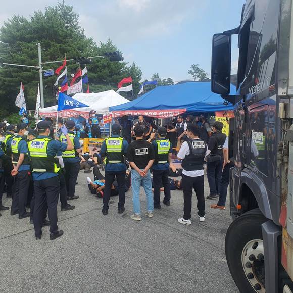 지난 14일 화물연대가 이천공장 진·출입로에 누워 차량 통행을 방해하고 있다. [사진=하이트진로]
