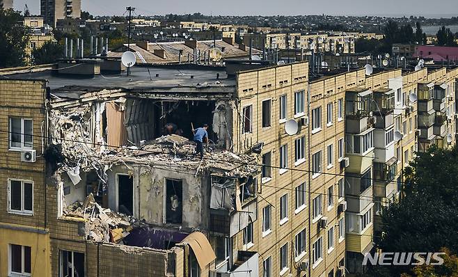 [니코폴=AP/뉴시스] 15일(현지시간) 우크라이나 니코폴에서 한 남성이 러시아군의 포격으로 파괴된 아파트를 청소하고 있다. 2022.08.16.