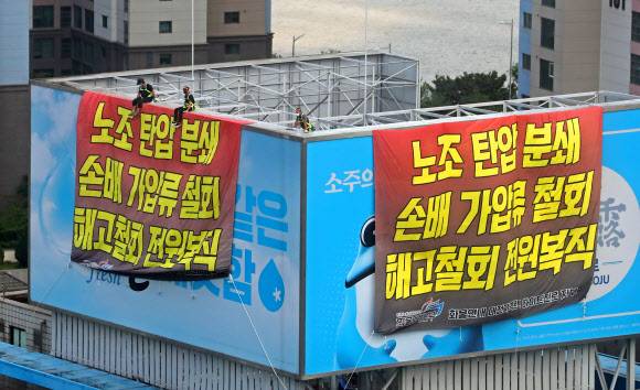 민주노총 공공운수노조 화물연대 조합원들이 16일 서울 강남구 청담동 하이트진로 본사 옥상에서 ‘노조탄압 분쇄, 손배가압류 철회, 해고 철회 전원복직’의 글귀가 적힌 대형 현수막을 설치하고 고공 농성을 하고 있다. 화물연대 노동자들은 사측에서 요구안을 수용할 때까지 투쟁을 이어 가겠다고 밝혔다.연합뉴스