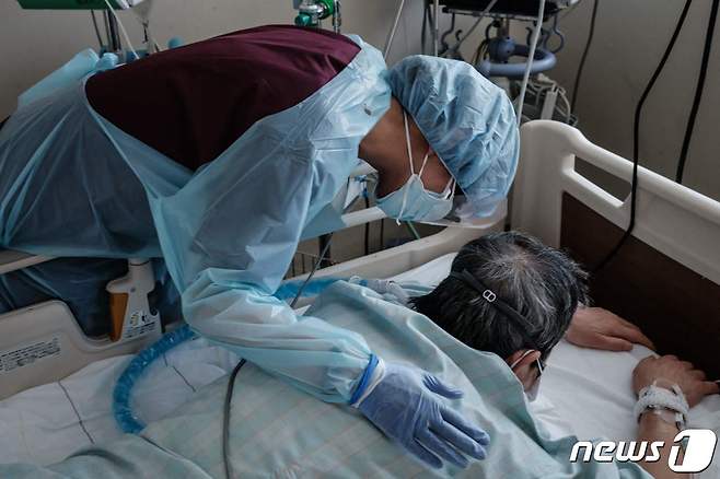 3일 (현지시간) 일본 삿포로에 있는 홋카이도 대학병원에서 방호복을 입은 의료진이 엎드려 있는 코로나19 환자를 위로하고 있다. ⓒ AFP=뉴스1 ⓒ News1 우동명 기자