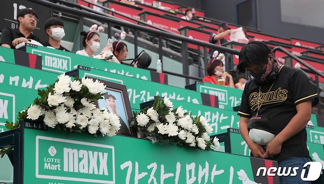 17일 부산 동래구 사직구장에서 고 캐리 마허 전 교수의 별세 소식을 들은 팬이 캐리 마허가 자주 이용하던 좌석에 마련된 추모장소에서 묵념하고 있다. 2022.8.17/뉴스1