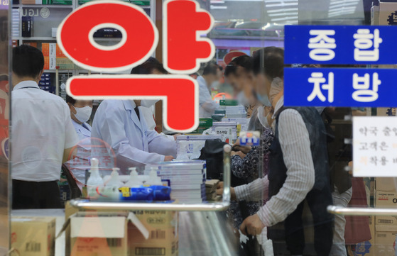 A pharmacy in downtown Seoul is crowded with customers on Wednesday. As Covid-19 continues and the shortage of cold medicine intensifies, the government is planning to ease the application of its so-called drug price interlocking system. According to the pharmaceutical industry on Wednesday, the Ministry of Health and Welfare is planning to hold a working-level consultation with companies to ease the application of the drug price interlocking system this month. The system lowers drug prices through negotiations with pharmaceutical companies when the amount of drugs covered by health insurance increases, in order to reduce drug spending. [NEWS1]