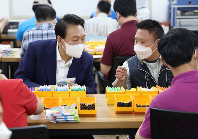 ▲ 윤석열 대통령이 18일 오후 서울 강남구 역삼동 충현복지관을 방문, 보호작업장에서 발달장애인 훈련생 및 근로인과 색연필 포장을 하면서 대화하고  있다.  연합뉴스