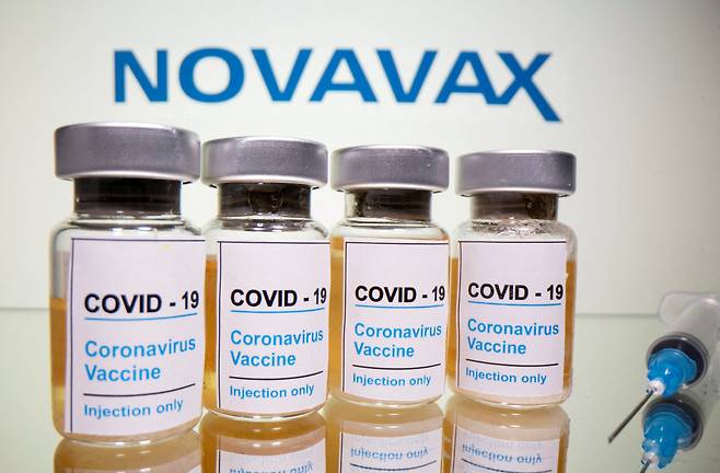COVID-19 vaccine vials and a medical syringe are seen in front of a Novavax logo. (Reuters-Yonhap)