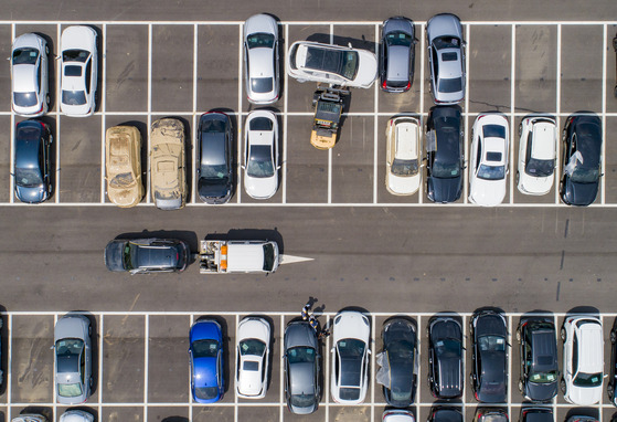 Workers move cars that have been submerged in rainwater after record heavy rains last Monday using forklifts and tow trucks at a temporary stockyard near Seoul Grand Park in Gwacheon, Gyeonggi, on Thursday. [YONHAP]