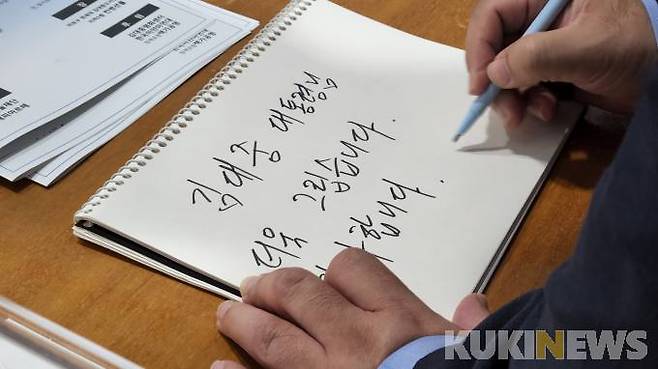 음악회 참석자들이 고 김대중 전 대통령을 그리워하면서 방명록에 글을 적고 있다.   사진=황인성 기자