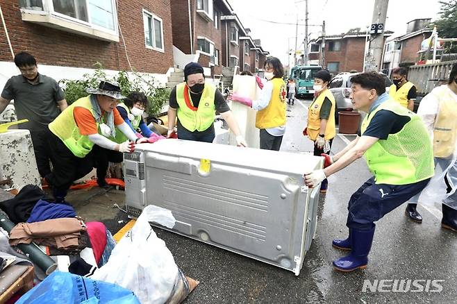 [수원=뉴시스]지난 11일 수원시의원 봉사단이 집중호우로 침수피해를 입은 권선구 평동 지역을 찾아 수해복구 활동을 펼치고 있다.(수원시의회 제공)