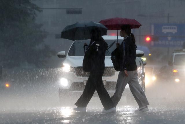 기습 폭우가 쏟아진 19일 오후 서울 시내 한 횡단보도에서 시민들이 우산을 쓰고 걸어가고 있다. 뉴시스