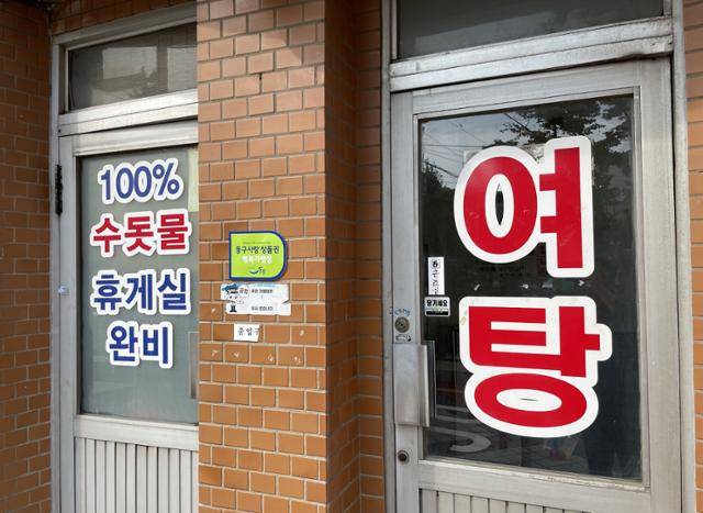 지난달 19일 인천 동구 송현동 세계목욕탕 출입문에 '100% 수돗물'이라고 쓰여 있다.