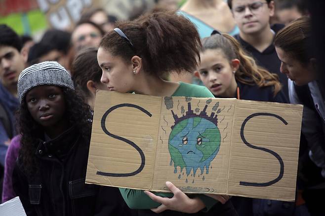 스페인에서 열리는 유엔 기후변화협약 당사국총회를 앞두고 전세계에서 기후변화 문제 해결을 촉구하는 시위가 동시에 벌어진 2019년 11월29일(현지시각) 포르투갈 리스본의 국회의사당 앞에서 한 청소년이 지구를 구해달라는 ‘에스오에스’(SOS) 손팻말을 들고 서 있다. 리스본/AP 연합뉴스