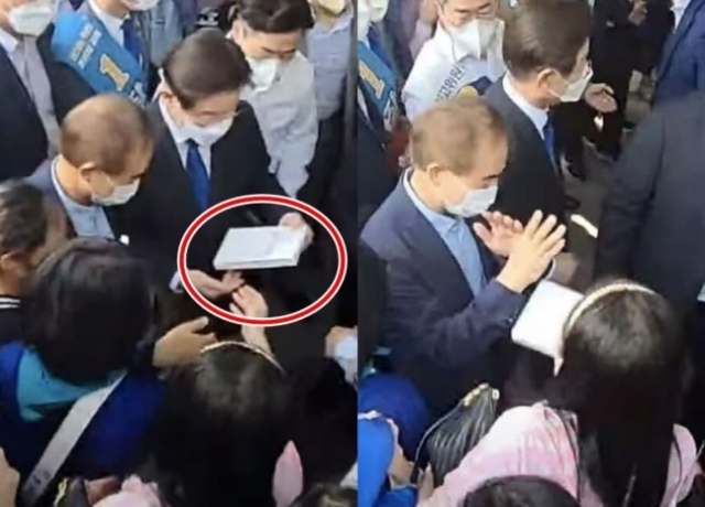 이재명 더불어민주당 대표 후보가 21일 광주 김대중컨벤션센터에서 한 여성이 사인 요청을 하며 건넨 책의 표지를 본 뒤 다시 돌려주고 있다. 온라인 커뮤니티 캡처