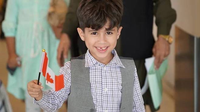 캐나다 국기를 흔들며 공항으로 입국하는 아프간 난민 어린이 [CBC 홈페이지]