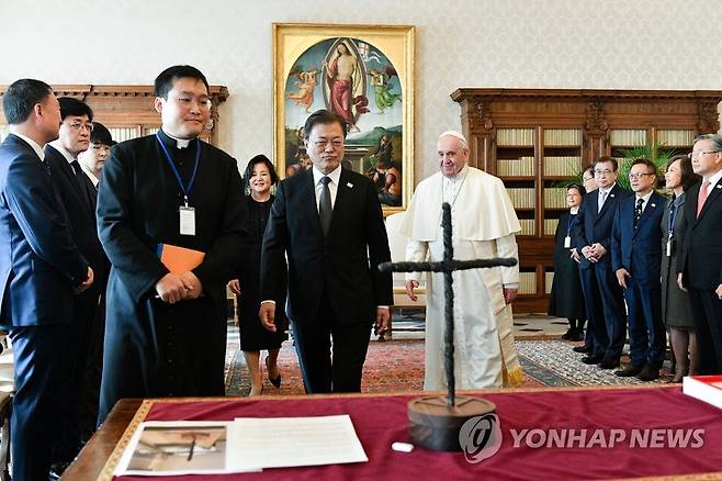 프란치스코 교황에게 평화의 십자가 설명 나선 문재인 대통령 2021년 10월 29일 교황청을 공식 방문한 문재인 전 대통령이 프란치스코 교황과 단독 면담에 앞서 DMZ 철조망을 잘라 만든 평화의 십자가를 설명하기 위해 이동하고 있다. [교황청 제공. 재판매 및 DB 금지]