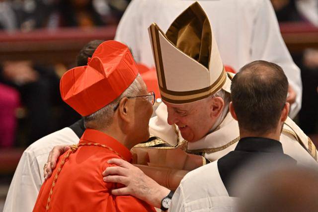 프란치스코 교황이 27일 오후(현지시간) 바티칸 성 베드로 대성당에서 열린 추기경 회의에 참석해 신임 추기경 서임식 진행 중 유흥식 라자로(왼쪽) 추기경에게 빨간색 비레타(각모)를 씌우고 그를 가볍게 포옹하고 있다. AFP=연합뉴스