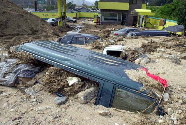 태풍 루사가 지나간 2002년 9월 3일 강원 동해시 삼화동의 한 주유소 주차장에 급류에 휩슬려 토사에 매몰된 차량들이 그대로 방치돼 있다. 한국일보 자료사진
