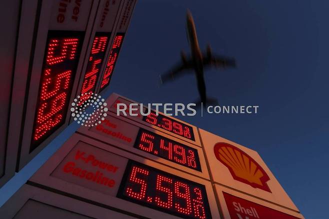 An aircraft flies over a sign displaying current gas prices as it approaches to land in San Diego, California, U.S., February 28, 2022. REUTERS/Mike Blake/File Photo/사진=로이터=뉴스1