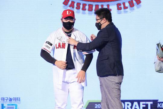 대구고 투수 이로운이 15일 오후 서울시 중구 웨스틴조선 서울에서 열린 프로야구 신인 드래프트에서 1라운드 5순위로 SSG의 선택을 받은 뒤 류선규 단장으로부터 유니폼과 모자를 전달 받고 있다.KBO 제공