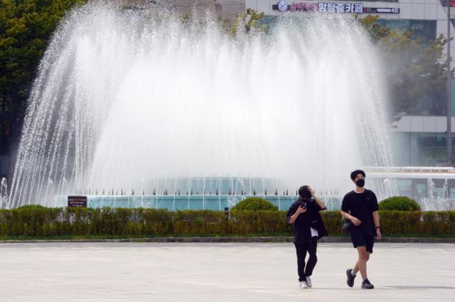 낮 기온이 30도까지 오른 14일 오후 광주 동구 5·18민주광장에서 시민들이 시원한 물줄기를 뿜어내는 분수대 옆을 지나고 있다. 뉴스1