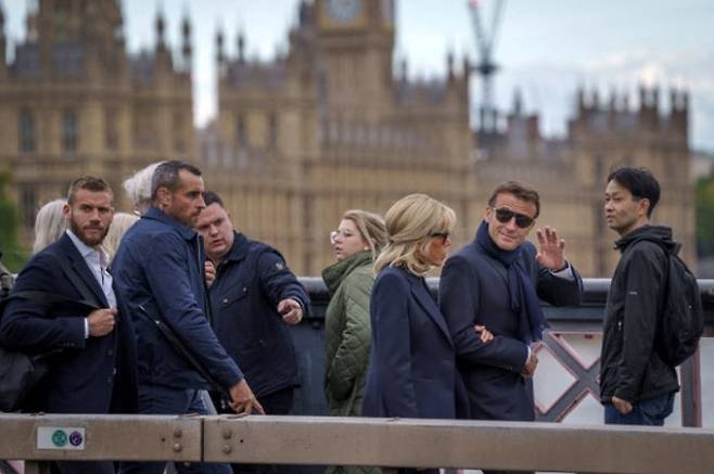 18일(현지시간) 엘리자베스 2세 영국 여왕 국장 참석을 위해 영국에 간 에마뉘엘 마크롱 프랑스 대통령(오른쪽 2번째)이 부인 브리지트 여사(오른쪽 3번째)와 나란히 선글라스를 낀 채 런던 거리를 걸으며 시민들한테 손을 흔들고 있다. 런던=EPA연합뉴스