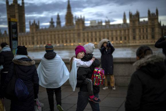 추위 속 밤샘 대기하는 참배객 - 밤 최저기온이 6도까지 내려간 추위 속에서도 엘리자베스 2세 영국 여왕을 직접 추모하려는 시민들의 발길이 이어지고 있는 가운데 18일 여왕의 관이 있는 런던 웨스트민스터홀 외부에서 대기 중이던 한 조문객이 잠든 어린이를 안고 있다.런던 AP 연합뉴스