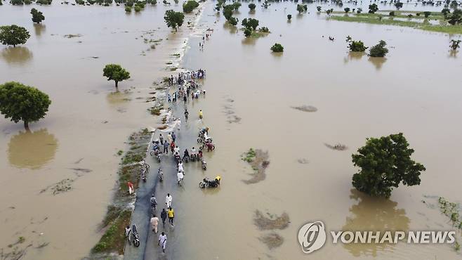 지난 19일 나이지리아 홍수로 사람들이 물을 헤치며 걷는 모습 [AP 연합뉴스 자료사진. 재판매 및 DB 금지]