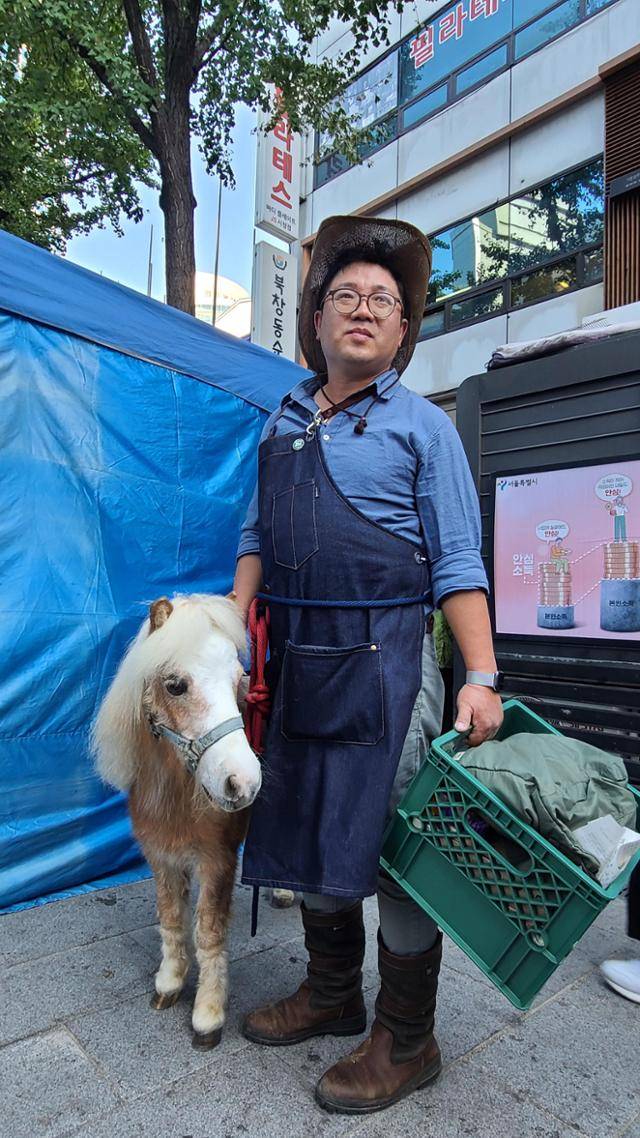 송대근씨가 24일 오후 서울시청역 인근에서 반려 말 고셔와 함께 기후정의행진에 참여하고 있다. 이유진 기자