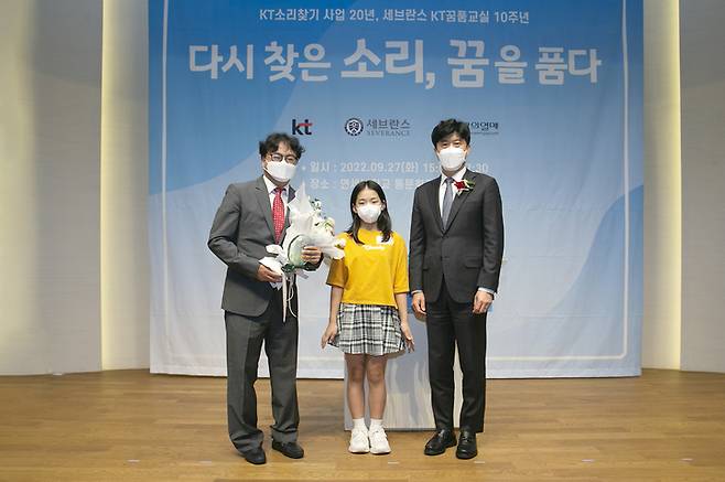 [서울=뉴시스] KT와 연세의료원이 27일 오후 서울 서대문구 연세대 동문회관에서 소리찾기 20년 및 KT 꿈품교실 10주년 기념식을 열어 그간의 성과를 돌아보는 자리를 가졌다. KT 김무성 상무(사진 오른쪽)와 소리찾기 수혜아동 노혜담 어린이(사진 중앙), 최재영 교수(사진 왼쪽)가 기념촬영을 하는 모습. (사진=KT 제공) 2022.9.28 *재판매 및 DB 금지