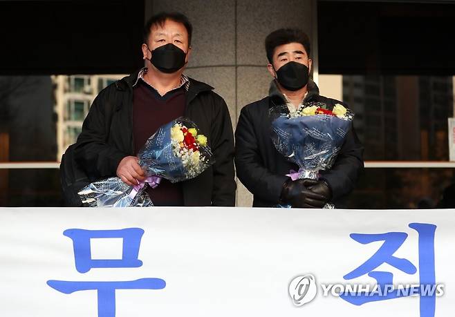 31년만에 무죄 선고받은 '낙동강변 살인사건' 누명 피해자들 경찰 고문에 못 이겨 살인죄 누명을 쓴 채 21년간 억울한 옥살이를 한 '낙동강변 살인사건' 피해 당사자 최인철(왼쪽)씨와 장동익씨가 작년 2월 4일 오전 부산고법에서 열린 재심 선고 공판에서 무죄를 선고받은 뒤 꽃다발을 들고 있는 모습. [연합뉴스 자료사진]