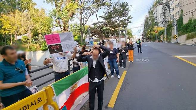 한 이란 남성이 28일 오후 서울 용산구 주한 이란이슬람공화국대사관 인근에서 열린 집회에서 머리카락을 자르며 항의 시위를 하고 있다. 사진=임지혜 기자