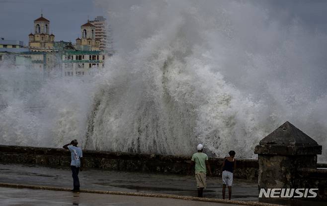 [아바나=AP뉴시스] 28일(현지시간) 쿠바 아바나에서 주민들이 허리케인 이언의 여파로 방파제에 부딪히는 거대한 파도를 바라보고 있다. 허리케인 이언이 휩쓸고 간 쿠바는 나무가 통째로 뽑히고 담배 농장이 파괴됐으며 전력망이 붕괴해 전역에 정전 사태가 빚어졌다. 2022.09.29.