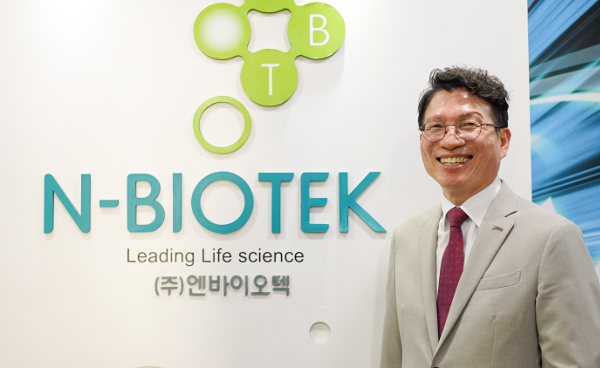 김대용 엔바이오텍 대표가 지난 26일 경기도 부천 본사의 회사 로고 앞에서 밝게 웃고 있다.