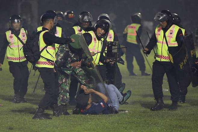1일 폭동이 발생한 인도네시아 자바의 칸주르한 경기장에서 경찰과 보안요원이 한 축구팬을 제압하고 있다. 자바/AP 연합뉴스