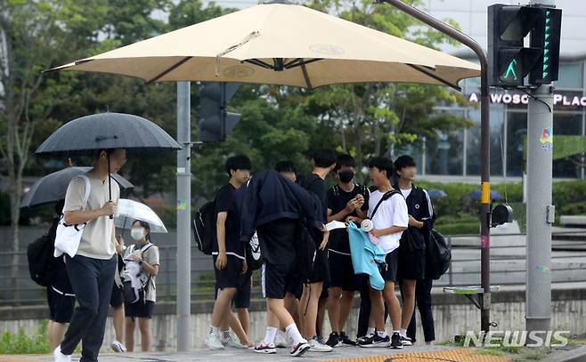[서울=뉴시스] 추상철 기자 = 소나기가 내린 7일 오후 서울 도심에서 우산을 준비하지 못한 학생들이 대형 그늘막 아래에 모여 비를 피하고 있다. 2022.07.07. scchoo@newsis.com