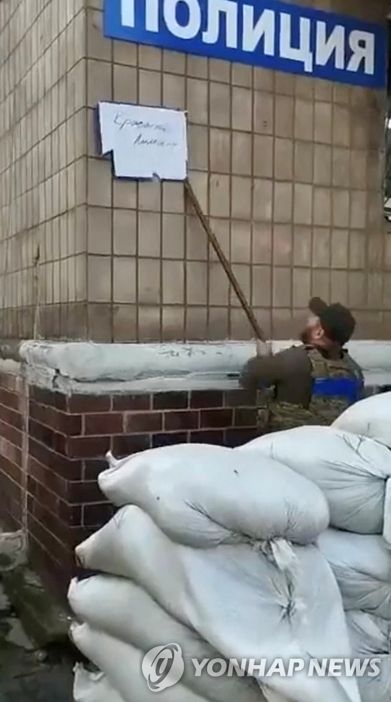 러시아 게시물 떼는 우크라이나군 (로이터=연합뉴스) 1일(현지시간) 우크라이나군이 리만시의 경찰서 외벽에 붙은 러시아 게시물을 떼고 있다.