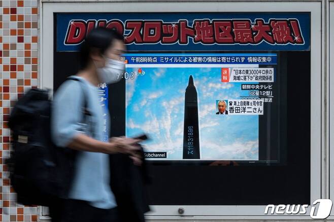 4일 일본 도쿄에서 한 시민이 북한의 미사일 발사 소식을 보도하는 TV 화면 앞을 지나고 있다. ⓒ AFP=뉴스1
